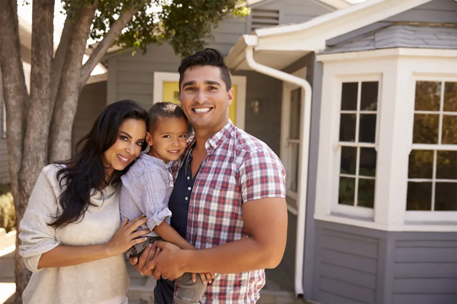 A hispanic family standing in front of their home.